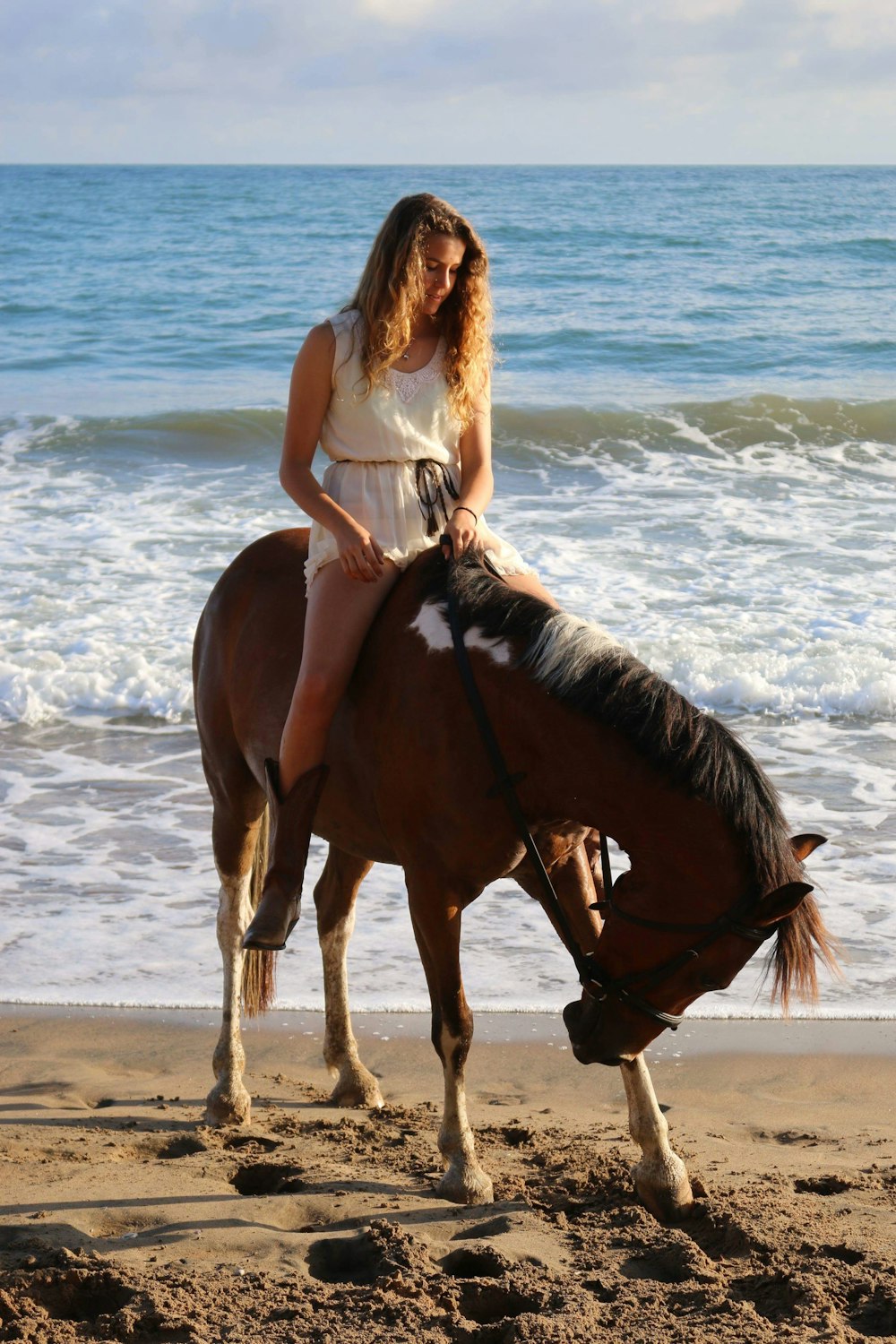 woman riding on brown horse near seashore