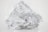 Crumbled foil loosely wrapped in a plastic sheet on a plain background. The plastic is transparent and the foil is shiny with a metallic luster.
