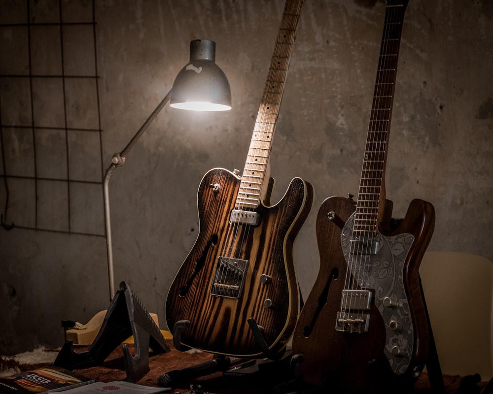 two brown guitars beside desk lamp