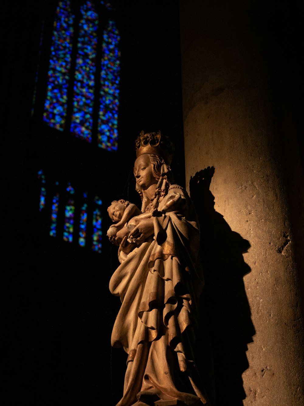 statue of woman carrying a child beside wall