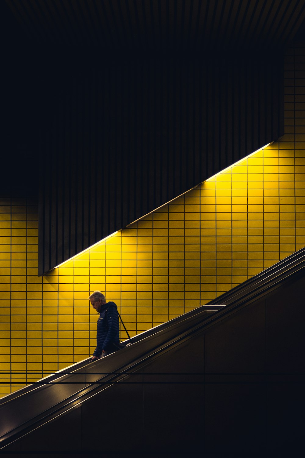 person in blue top riding escalator going down