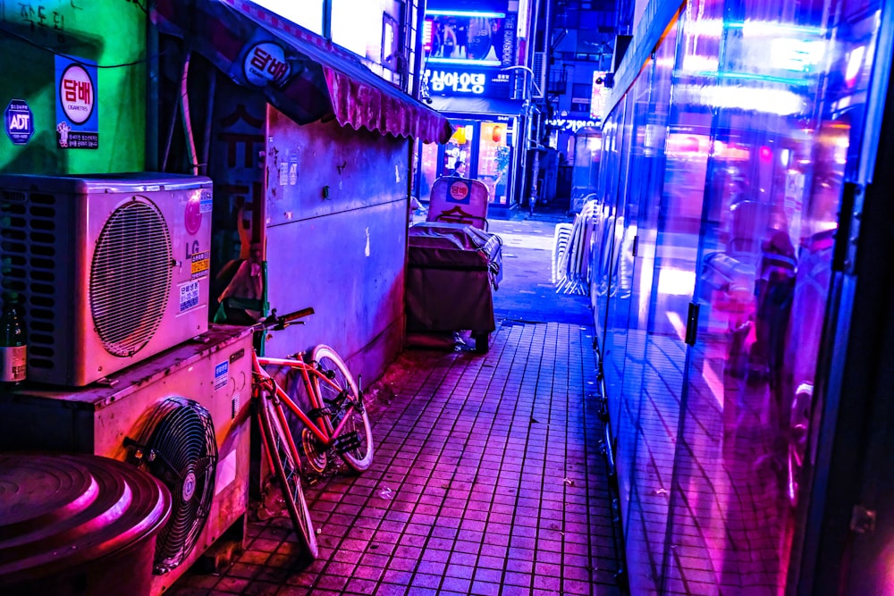 red and black bicycle parked near air condensing unit