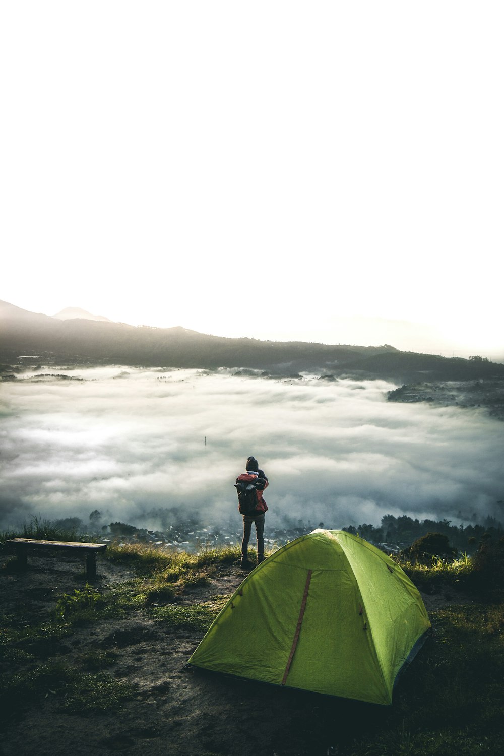person standing beside tent overlooking white clouds