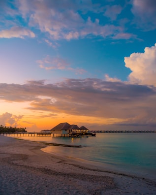 A serene overwater bungalow in Tahiti glowing under a pastel sunset.