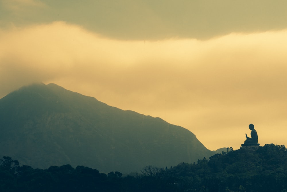 山を背景にヨガの投稿をしている人のシルエット写真