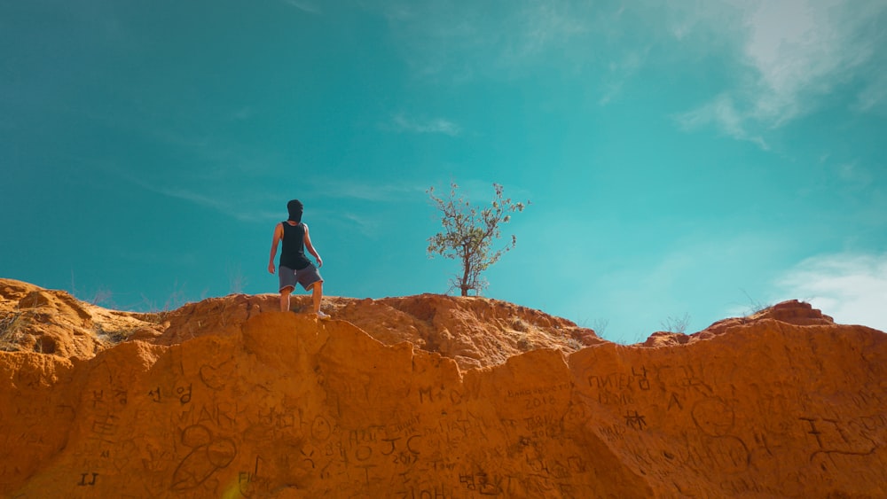 man in black tank top on brown rock formation