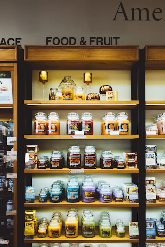 Wooden shelves displaying various scented candles in jars