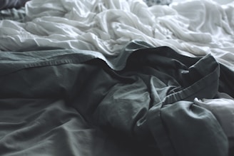 gray apparel beside white sheet