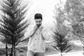 Hands adjusting a durable jacket cuff, with a backdrop of pine trees and cloudy skies