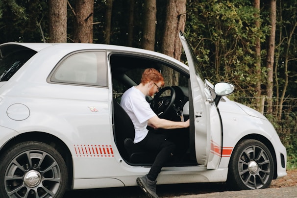 Instructor guiding a student through a pre-driving safety check beside a compact car.