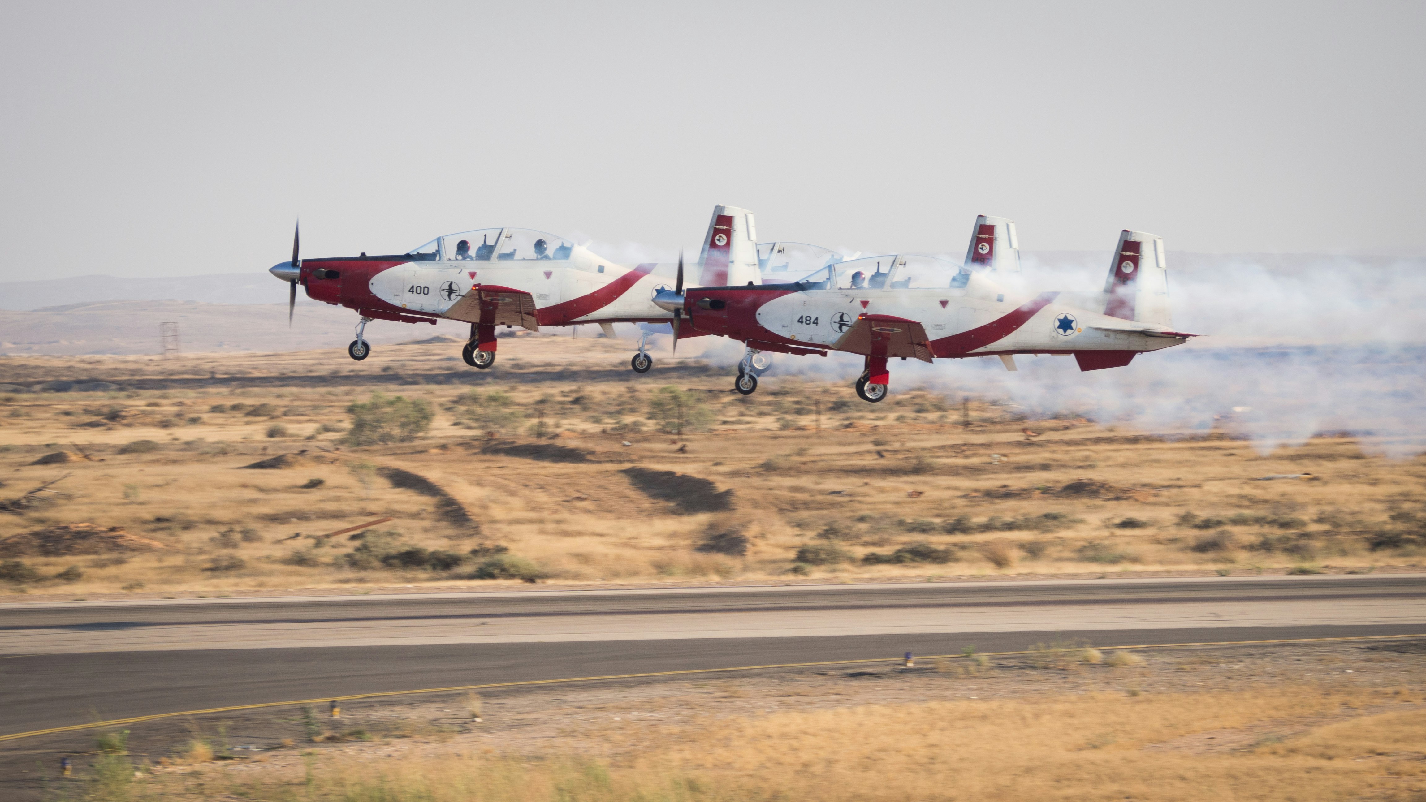 two red and white planes on dessert under white clouds