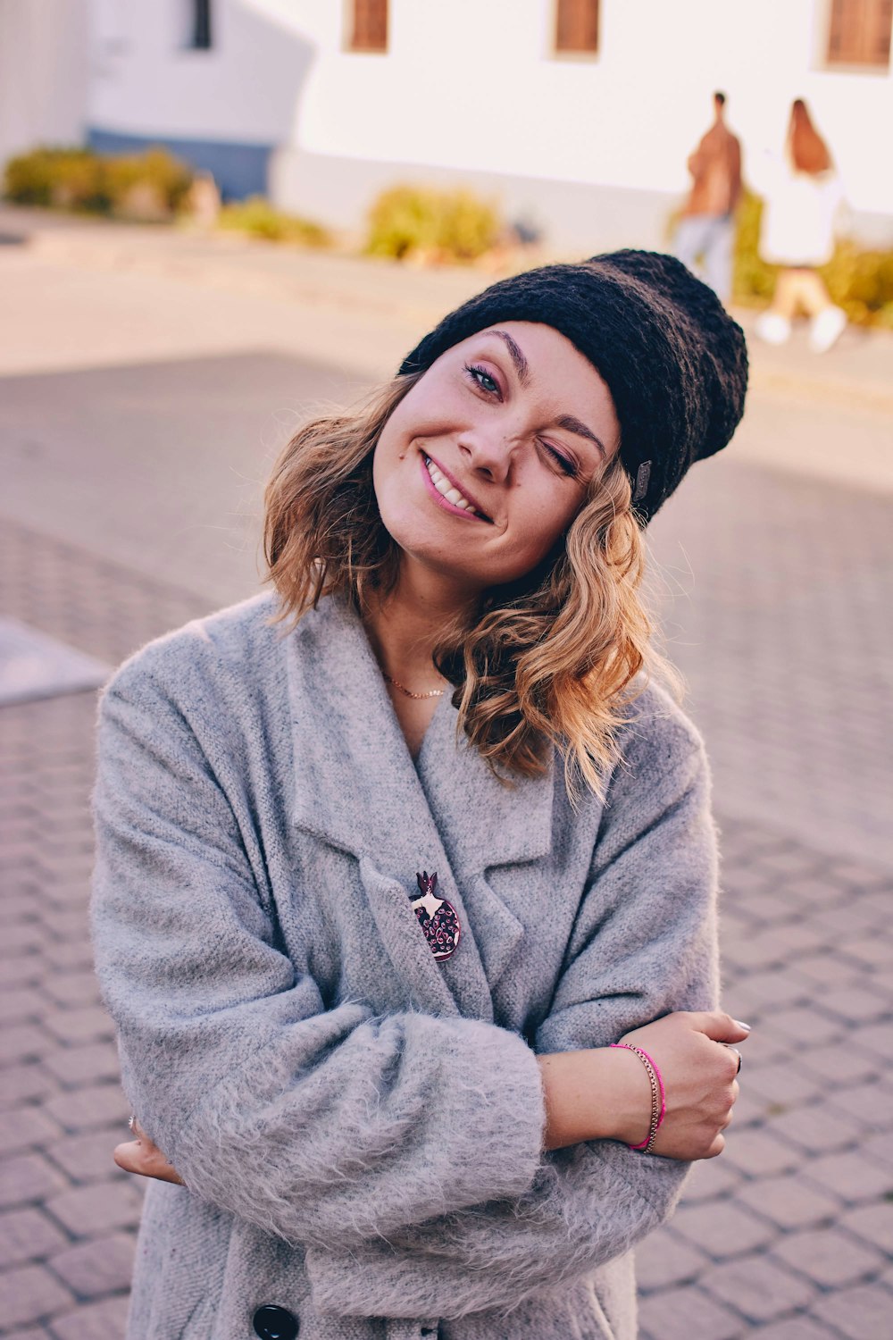 Mujer con chaqueta gris y gorro de punto negro haciendo gesto de cara