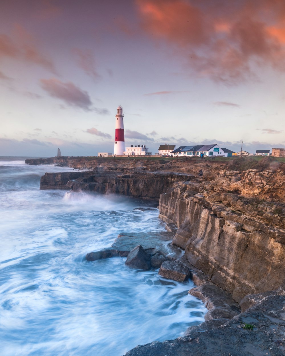 white and red lighthouse near ocean