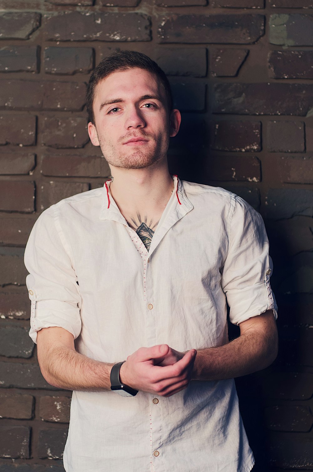 man wearing white dress shirt leaning on wall