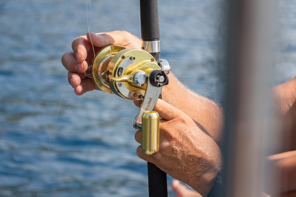 persona che tiene in mano un mulinello da pesca d'oro