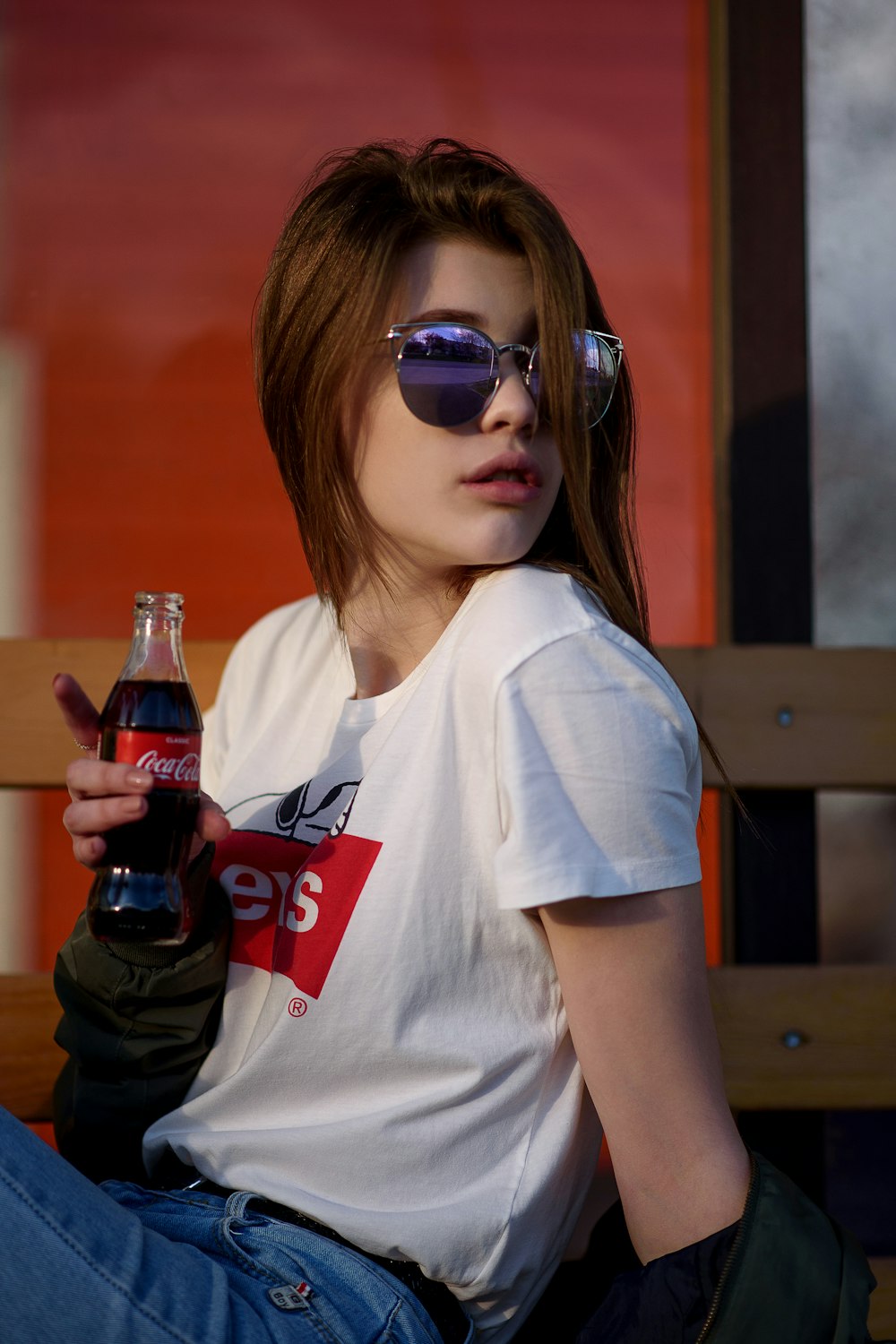 woman holding Coca-Cola bottle wearing white crew-neck Levis shirt