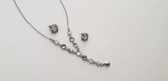 A delicate necklace and matching earrings set displayed on a soft velvet cushion.