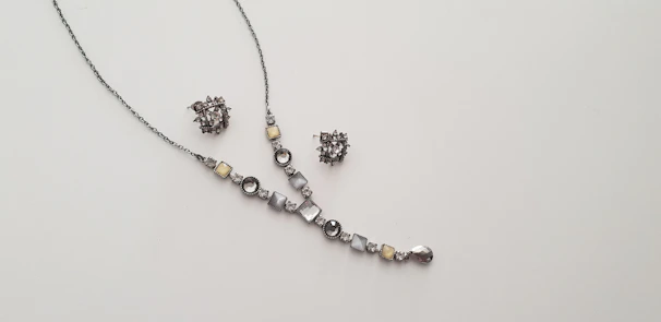 A delicate necklace and matching earrings set displayed on a soft velvet cushion.