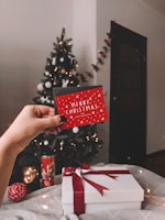 A festive scene featuring a hand writing a message inside a premium Christmas card.
