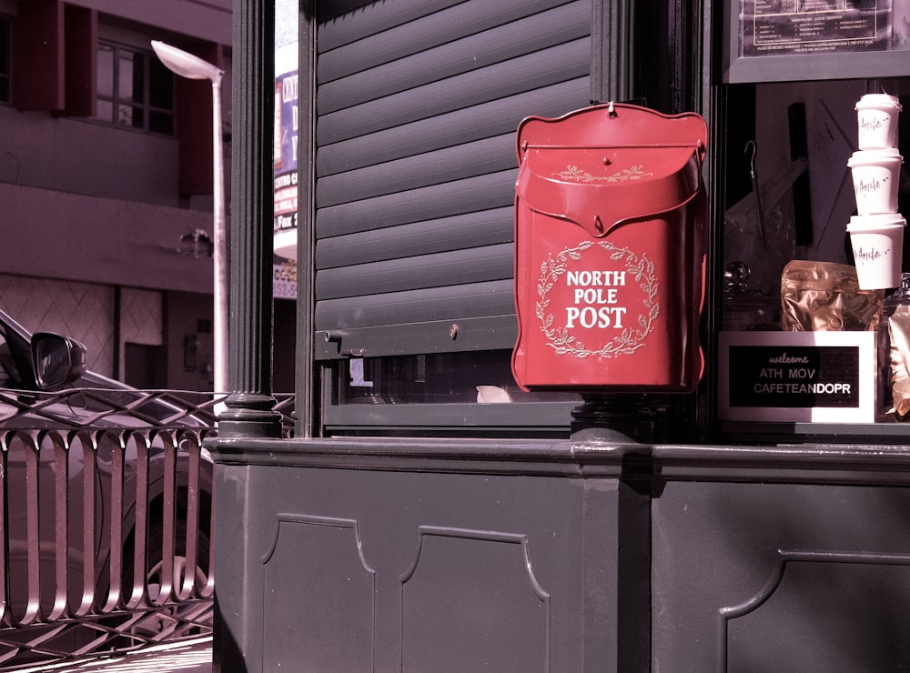 red North Pole post box near closed gray window