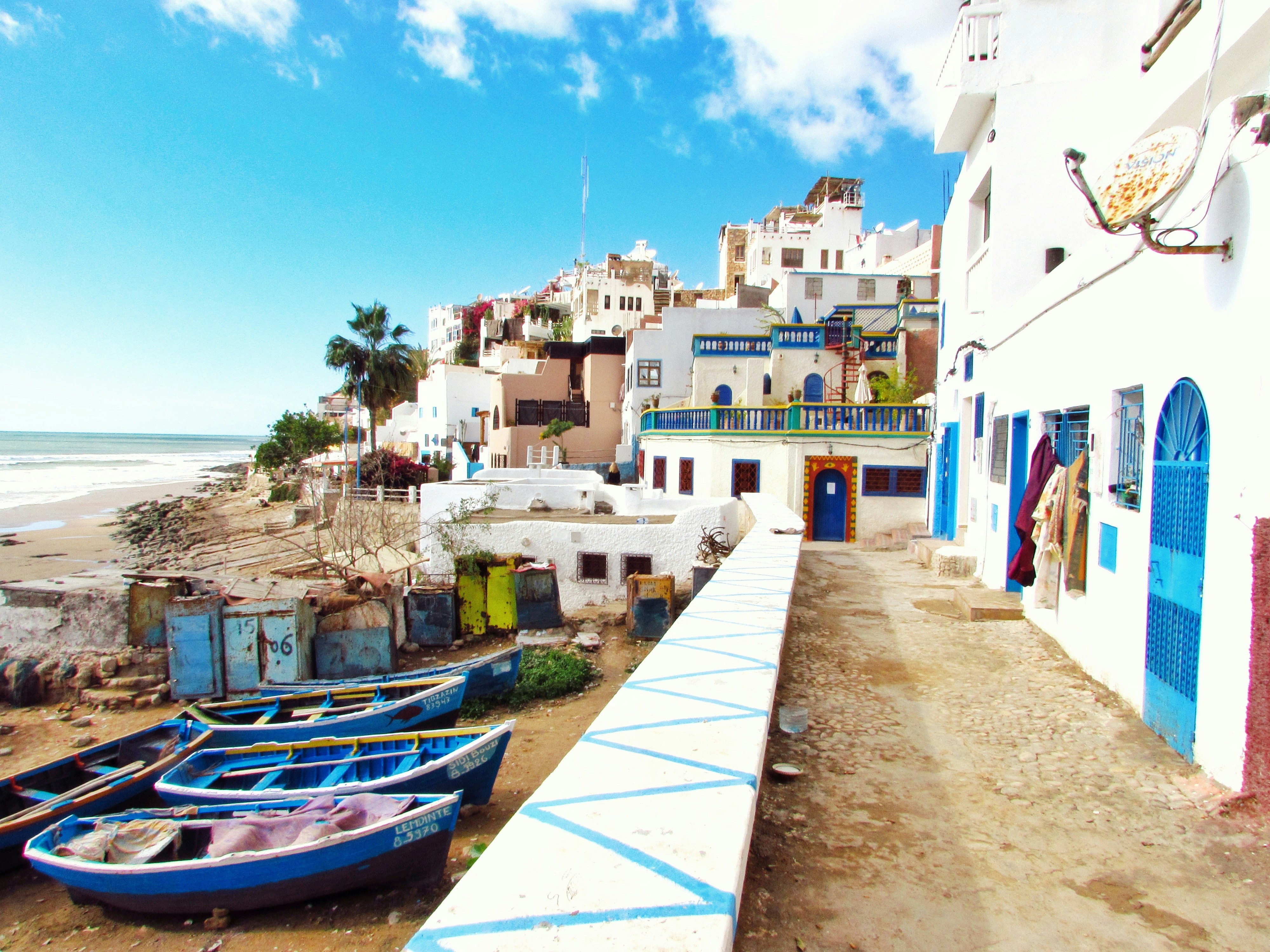 Essaouira blue and white medina walls with Atlantic Ocean and colorful fishing boats