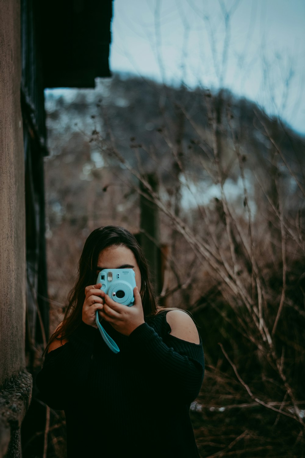 selective focus photography of woman using Fujifilm Instax Mini camera