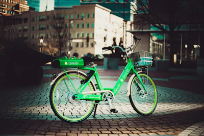 A vibrant electric bike parked by a city park with green trees and clear sky