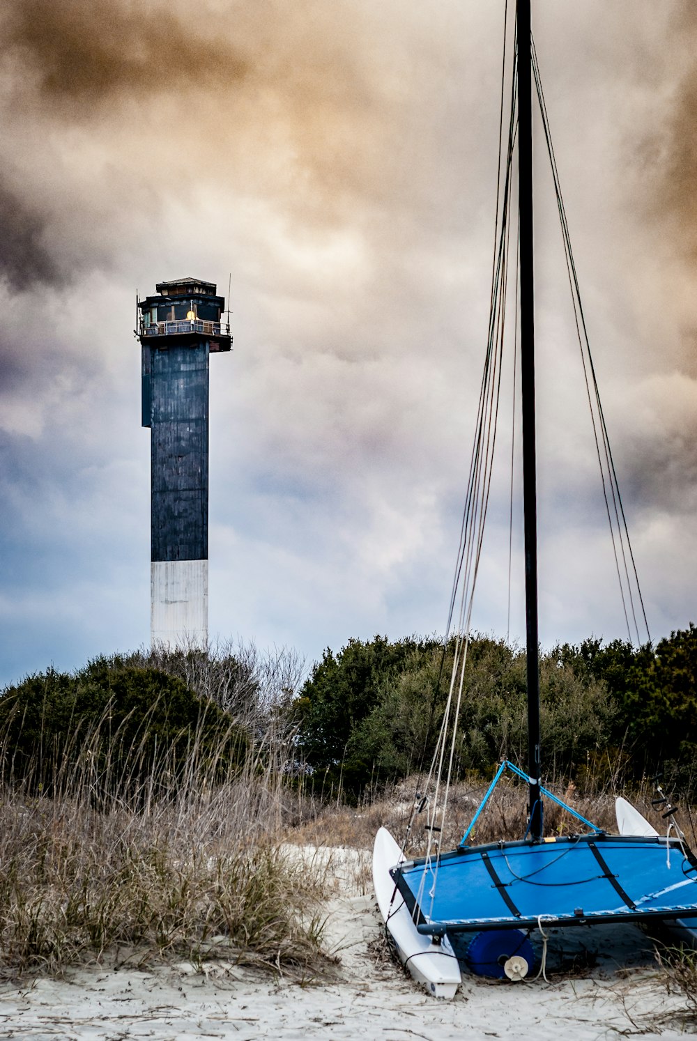 blue boat near lighthouse