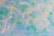 The image features a brick wall painted with blue, green, and hints of yellow. The colors blend together in a swirl-like pattern, giving the wall a vibrant, artistic look.