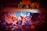 A vibrant graffiti mural with abstract shapes and patterns, featuring swirling designs in red, blue, orange, and black. Above the mural, there are faint images of human faces in a sepia tone, adding an element of intrigue and mystery.