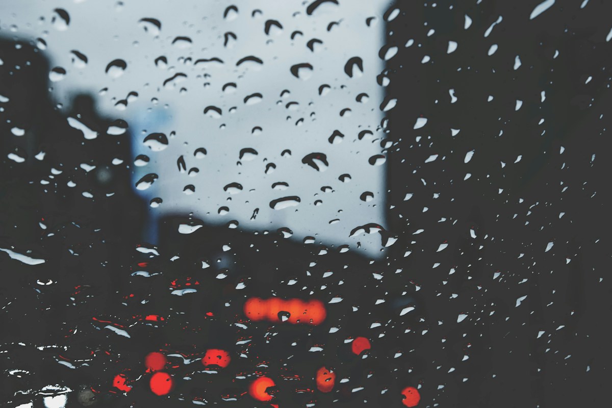 下雨天玻璃上的雨滴與模糊的城市車燈