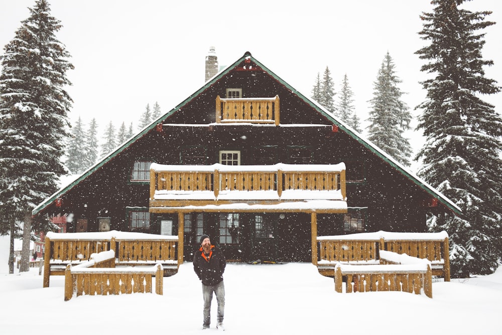 person standing beside brown wooden house during daytime