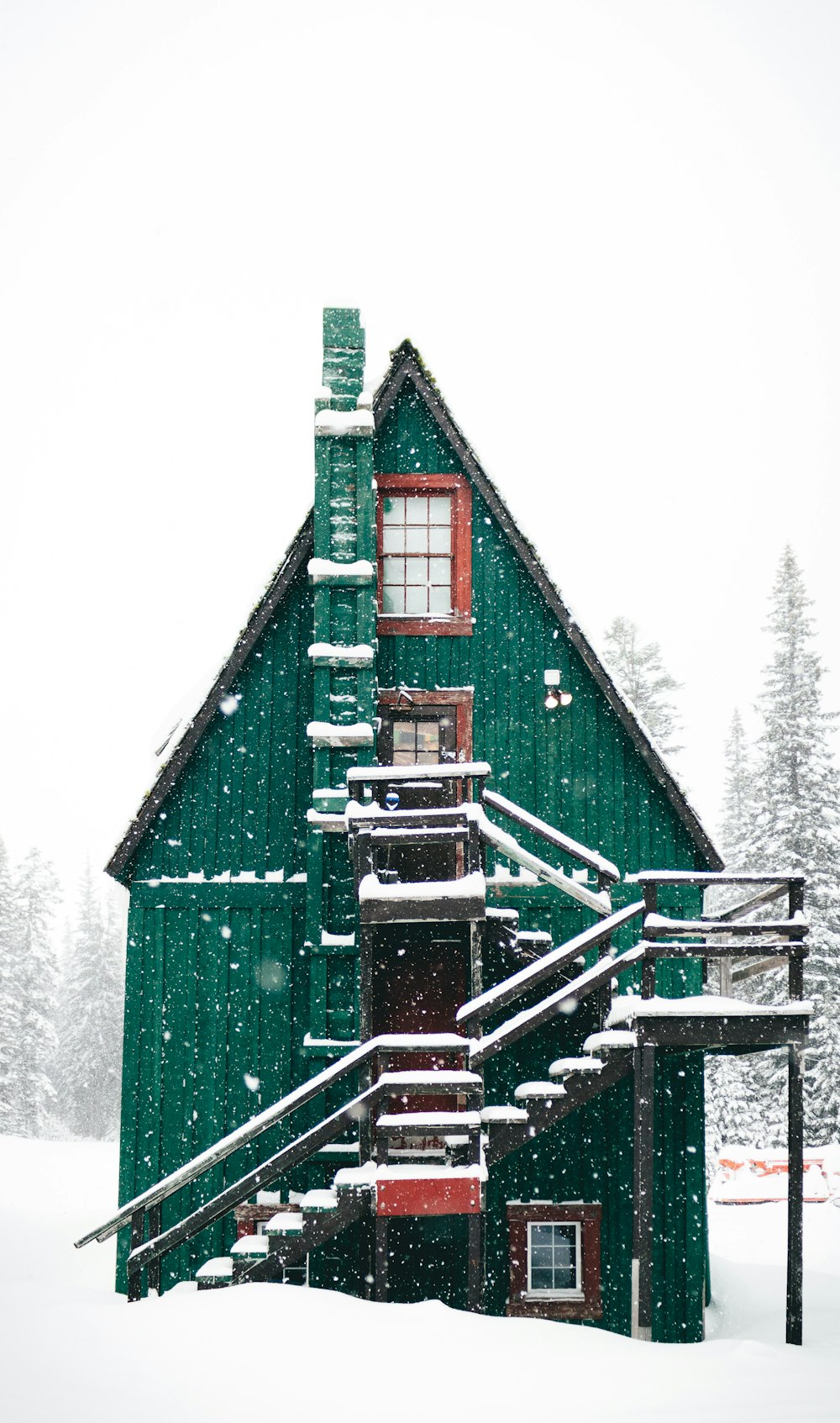 Zeitrafferfotografie von Schnee, der über ein grünes Holzhaus fällt