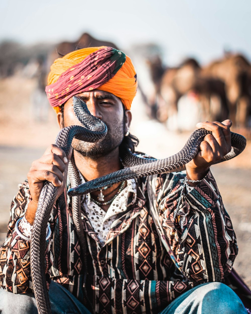 man holding two black snakes