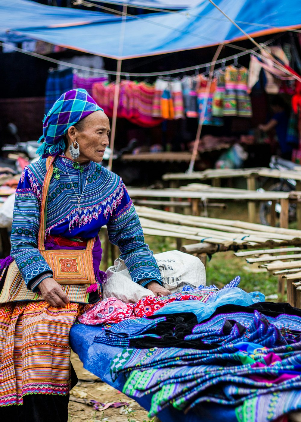 woman sitting on bench with displayed shawls