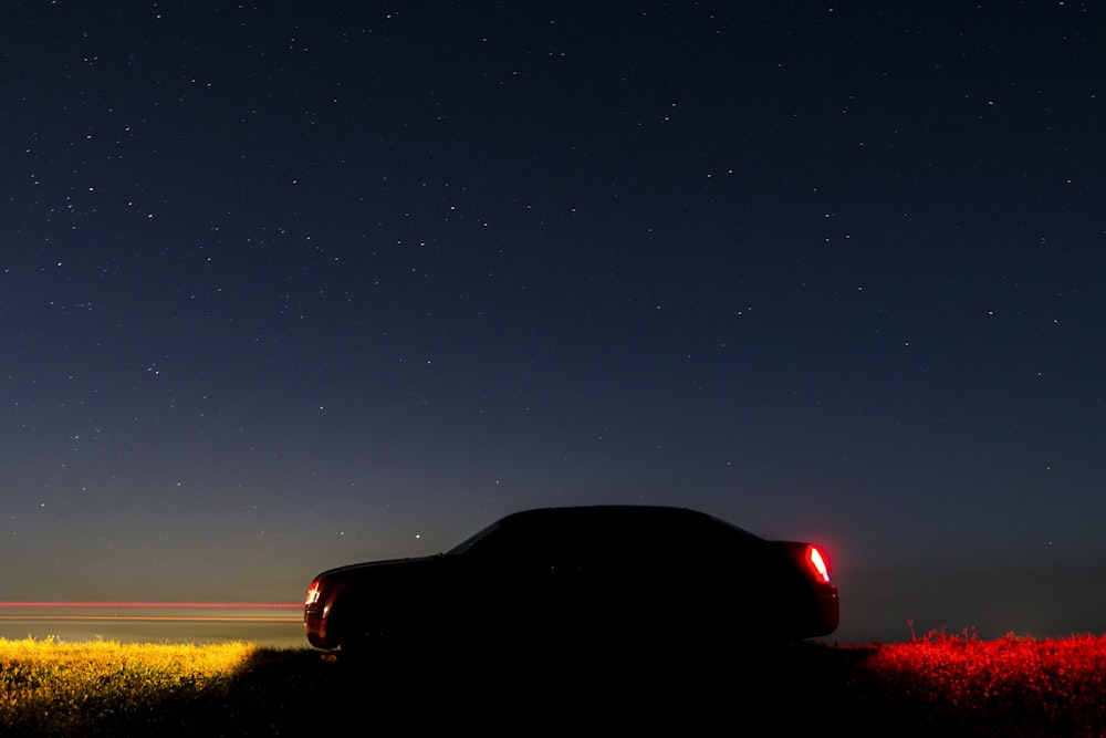 Silueta de coche bajo el cielo estrellado durante la noche