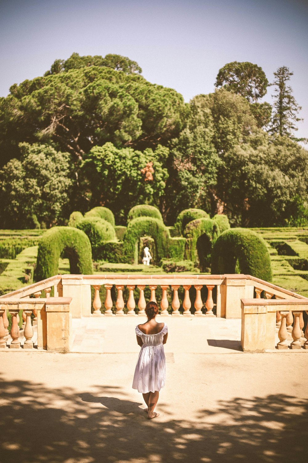 woman in white dress standing near green trees during daytime