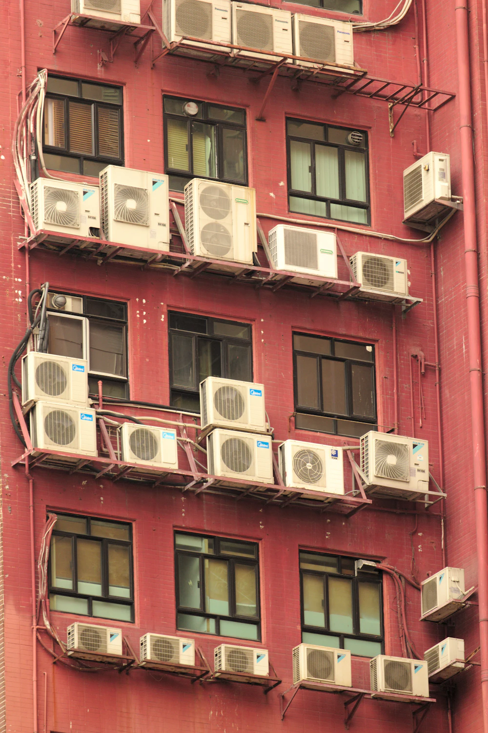 Row of white residential air conditioning condensing units installed outdoors