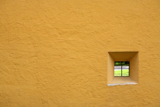 glass window pane with yellow concrete wall