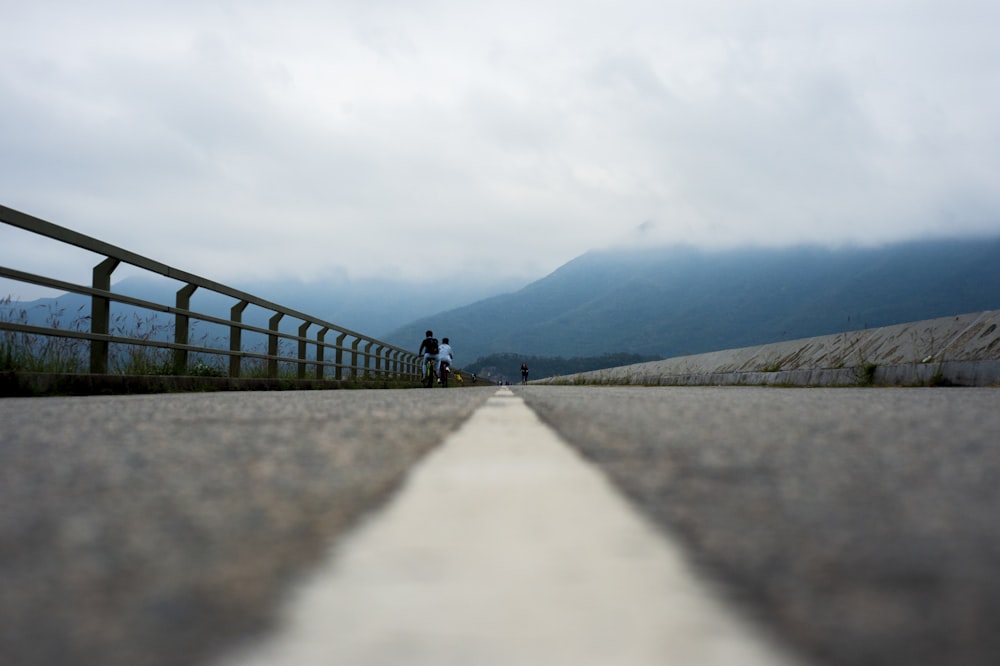 two persons riding bicycle on bridge at daytime