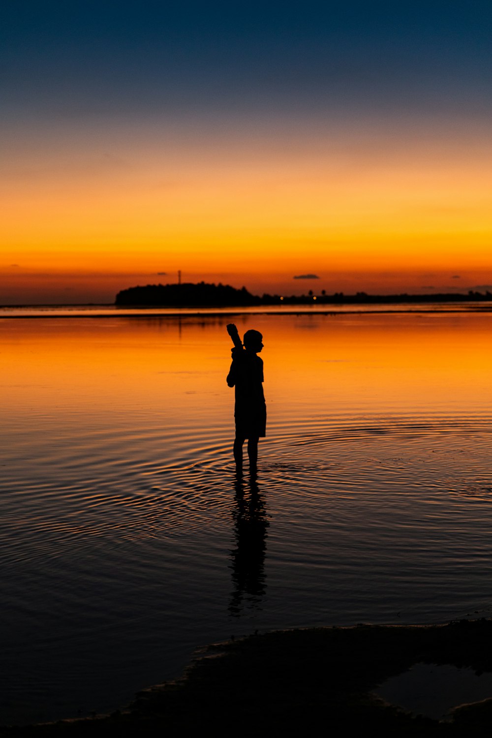 Silueta del hombre de pie en la orilla durante la hora dorada