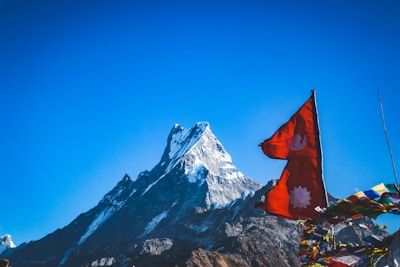 red flah near snow covered mountain during daytime
