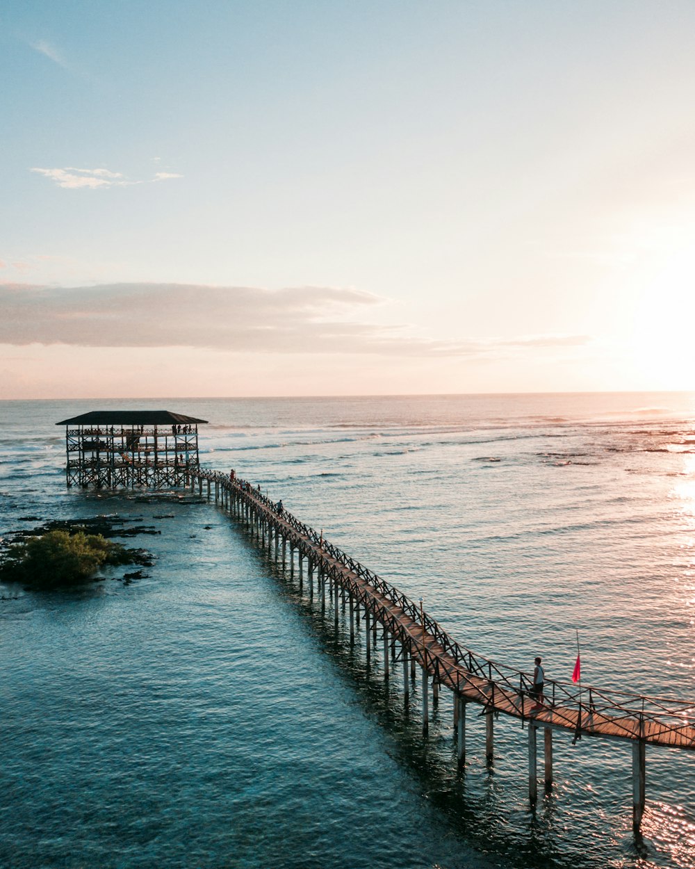 Fotografía aérea de un puente peatonal de madera sobre el mar azul