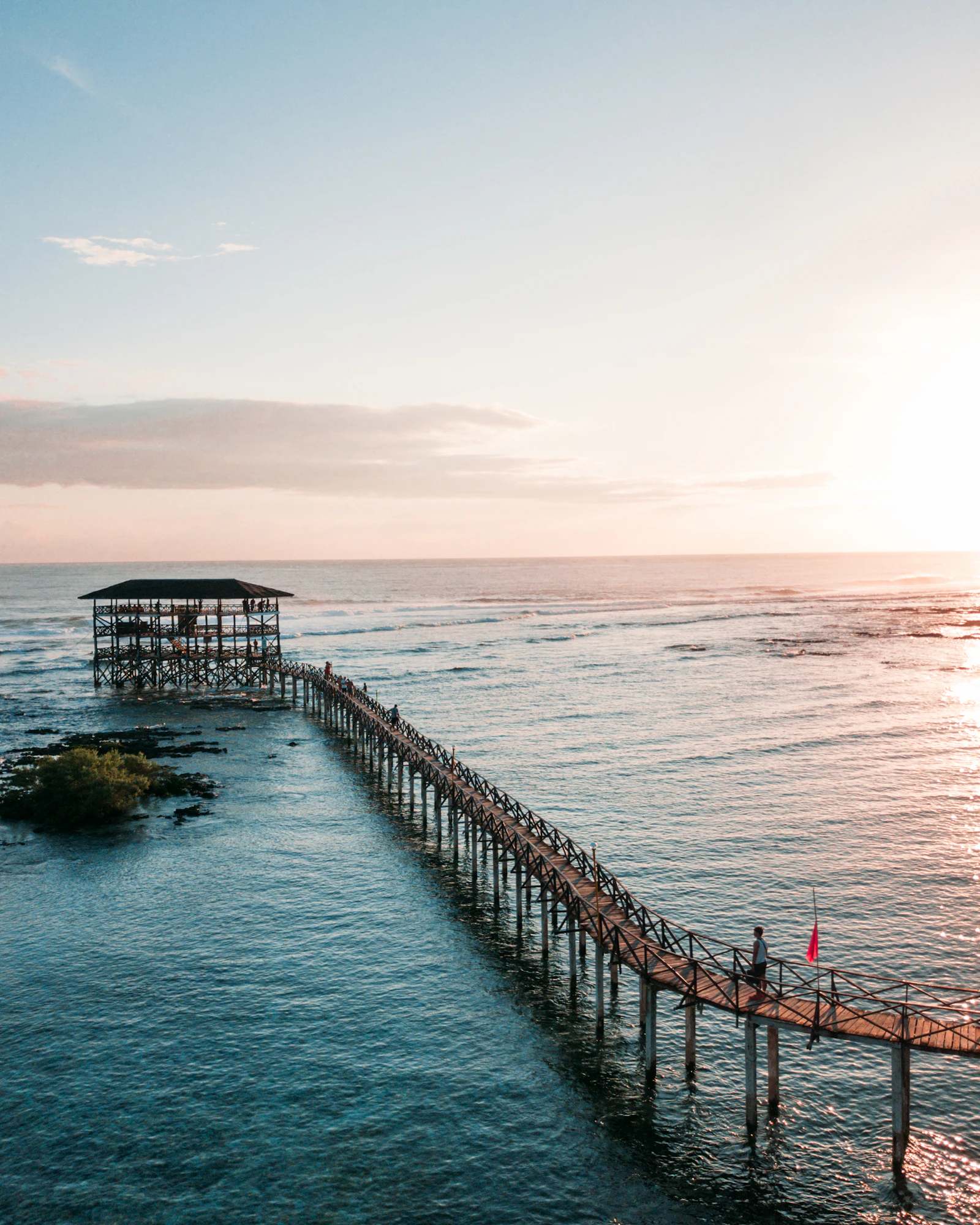 Aerial view of the Cloud 9 boardwalk and surf tower stretching into the sea at sunset, Siargao Island
