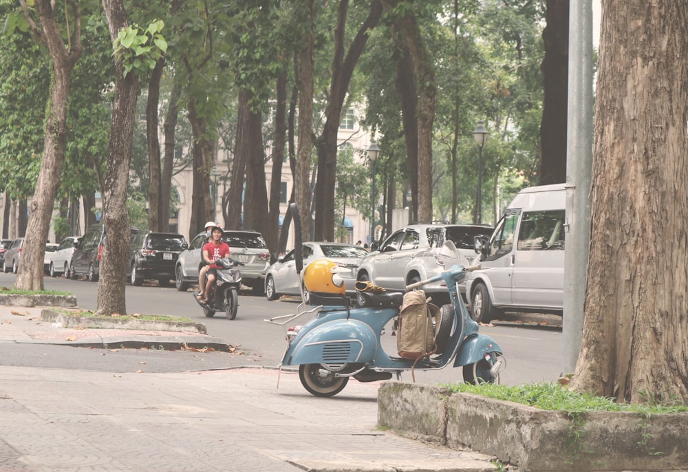 blue motor scooter parked beside road