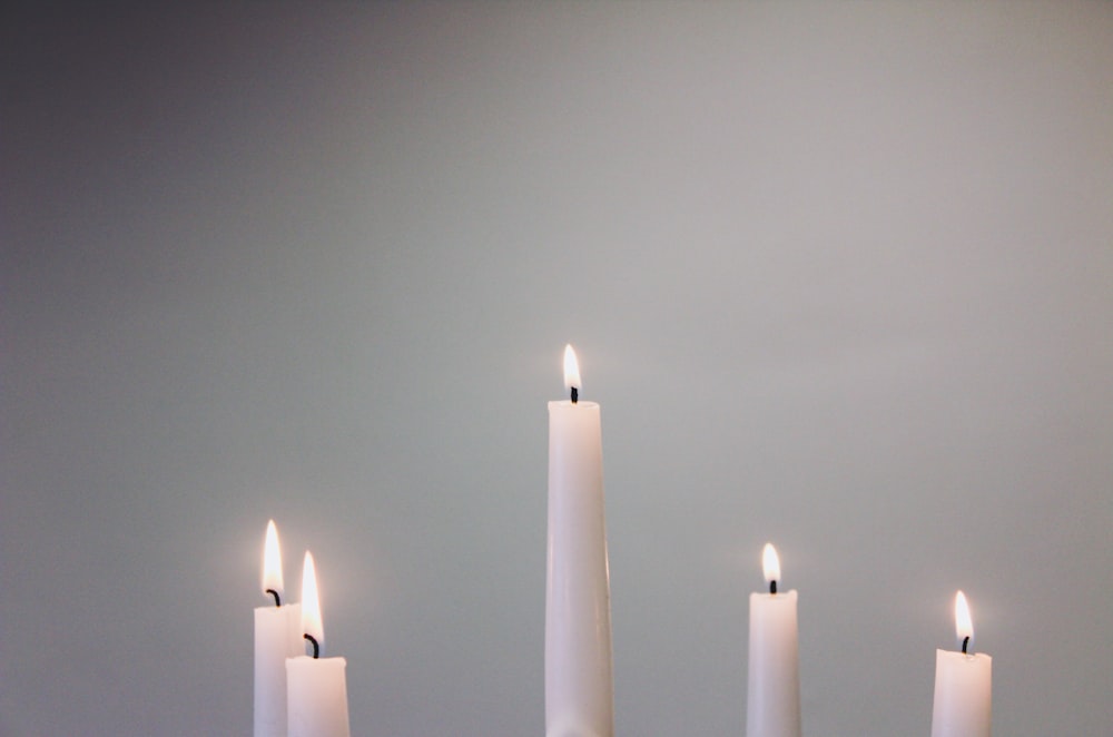 five lit white taper candles
