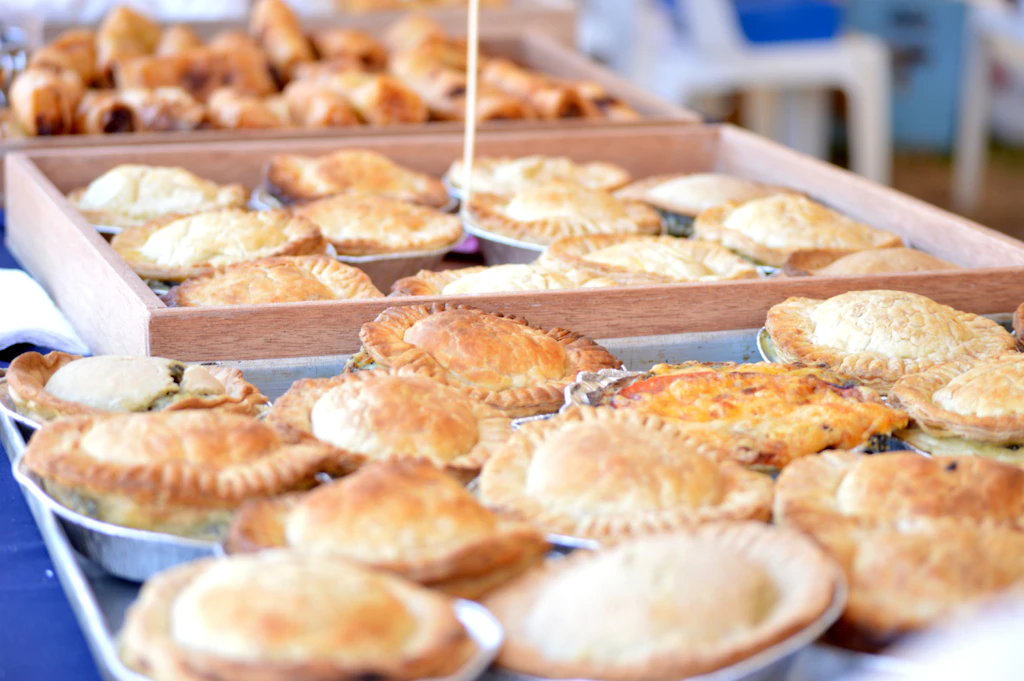 Trays of golden pies and savoury pastries laid out on a table for a function
