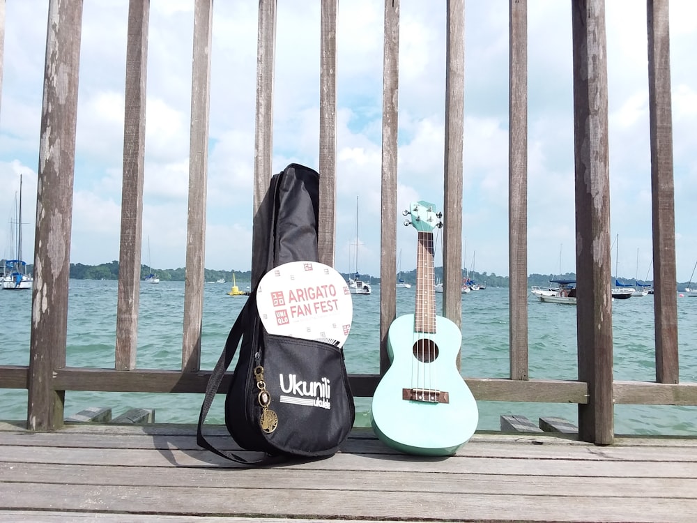 gray acoustic guitar beside black bag leaning on gray wall during daytime