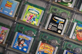 A collection of Game Boy Color cartridges is arranged in an overlapping pattern. The cartridges feature popular titles like Toy Story Racer, Power Rangers Time Force, F1 World Grand Prix, and Harry Potter. Each cartridge showcases its distinct cover art, emphasizing the diversity of games from different genres, including racing, adventure, and fantasy.