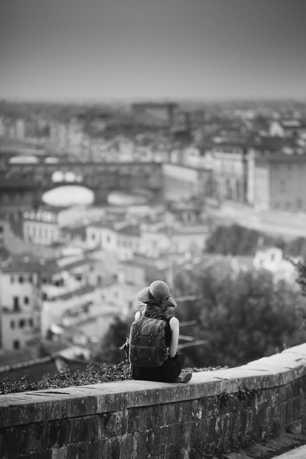 grayscale photography of woman sitting on concrete bench